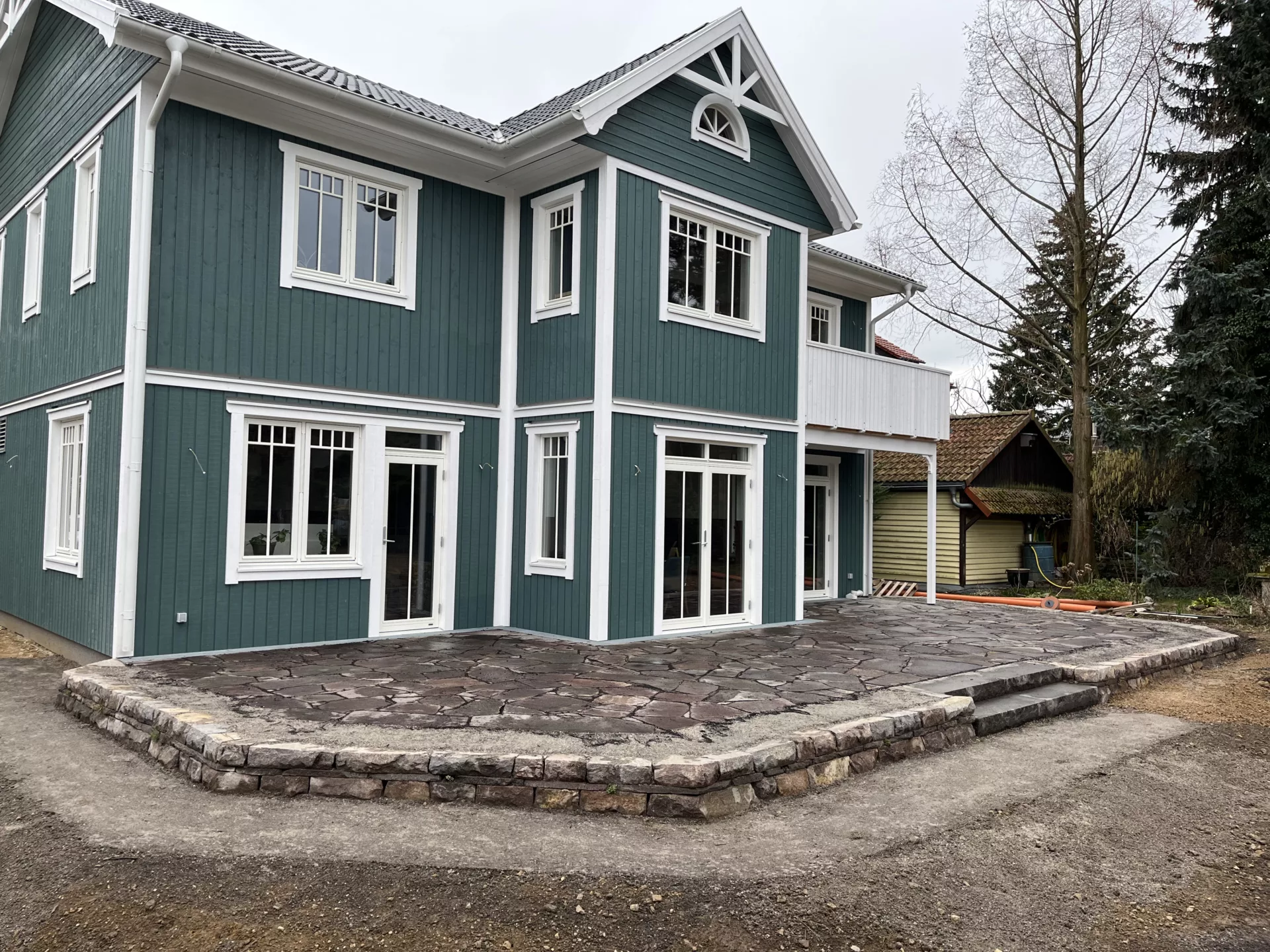 Sitzterrasse an Holzhaus mit Trockenmauer und Polygonplatten - Ital. Porphyr